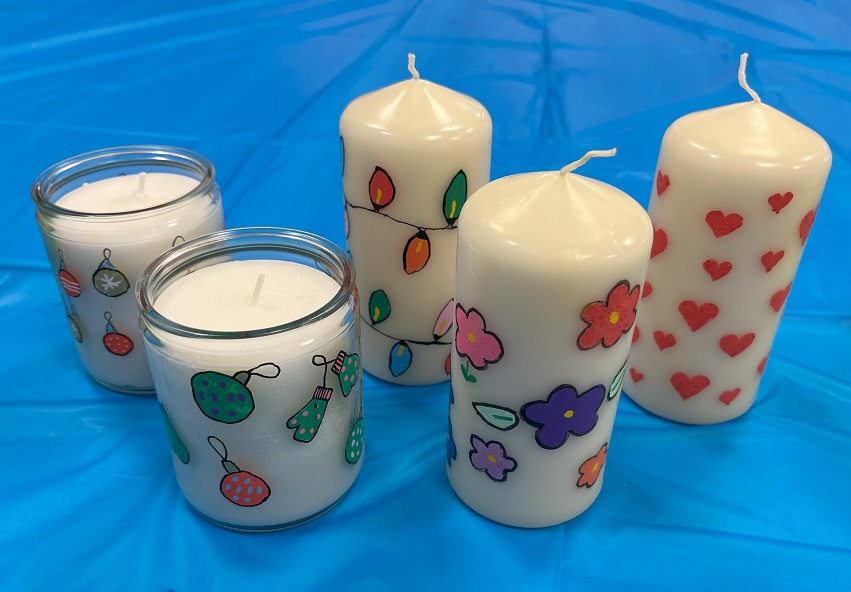 Candles painted in candle painting workshop. Jar candles and pillar candles painted with hearts and flower designs.