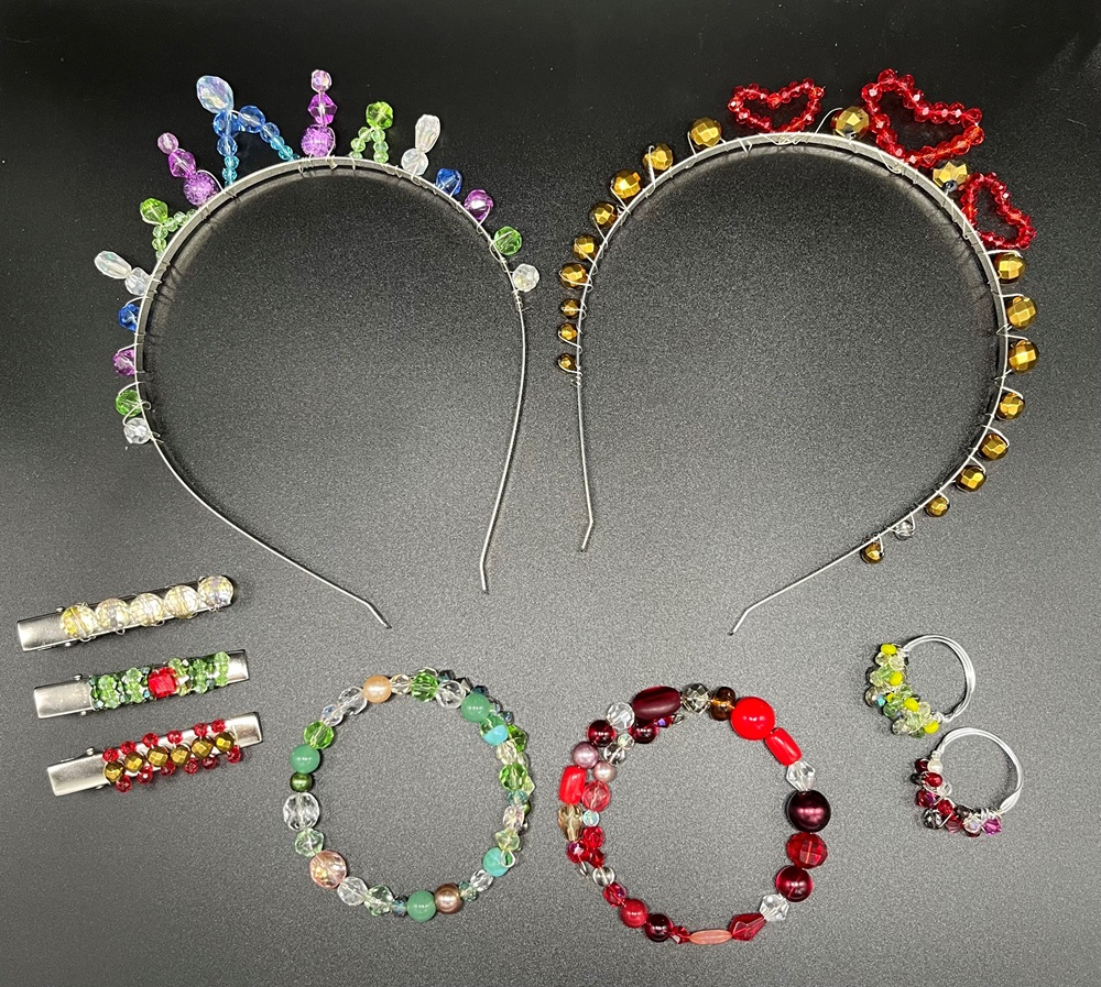 Selection of jewellery made in jewellery making workshop. Two crystal tiaras, one with red heart design, two beaded bracelets, two beaded cocktail rings and 3 crystal tie pins.
