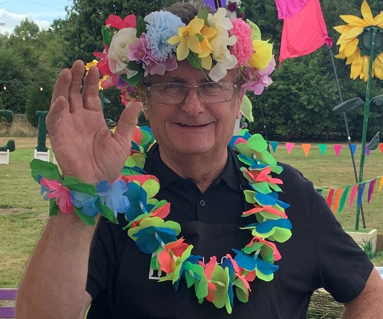 MAn at summer festival wearing colourful flower crown and hula lei.