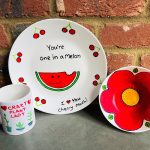 Painted plate, bowl and mug, featuring plants, fruits and flowers, painted at a corporate pottery painting workshop