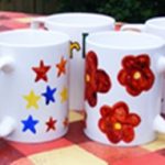 Finished mugs painted with coloured stars and red flowers painted at a corporate mug painting workshop