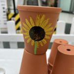 Terracotta plant pot painted with sunflower design on plant pot making workshop.