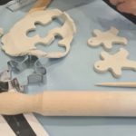 Clay workshop in progress - white clay with wooden rolling pin, gingerbread men cookie cutters and shapes cut out.