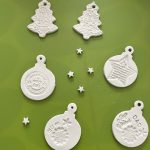 Finished white clay Christmas decorations in bauble and tree designs, embossed with Christmas shapes and patterns.