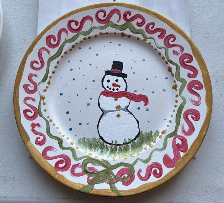 Christmas plate painted with snowman design at kids Christmas craft workshop for children.