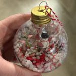 Close up of terrarium bauble with red and white gravel and small snowman decoration.