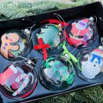 Box of six hand painted Christmas glass baubles in box. Designs feature gingerbread man, Santa, Christmas trees, candy cane and snowman, with green and red bows.