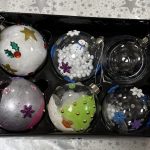 Box of six hand painted Christmas glass baubles in box. Designs feature holly, Christmas trees and snow. Two are filled with white fluff to look like snow.
