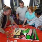 Team painting section of a painting in team building activity.