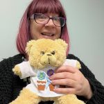 Holding a bear in a decorated T shirt made in charity team building activity.