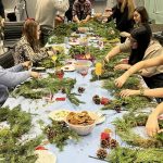 Close up of hands making fresh wreaths at wreathmaking workshop. Adding fresh moss to wreath rings.