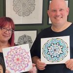 Two people holding their mandala drawing, drawn in corporate art class.