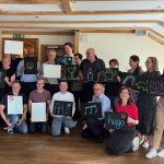 Team holding neon signs in various design made in corporate neon sign making workshop.