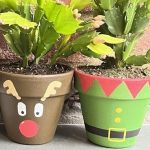 Pots painted with elf and reindeer design painted in Christmas plant pot painting workshop. Each pot holds a Christmas cactus.
