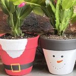 Pots painted with Santa and snowman design painted in Christmas plant pot painting workshop. Each pot holds a Christmas cactus.